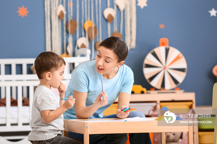 Nanny and cute little boy drawing at home