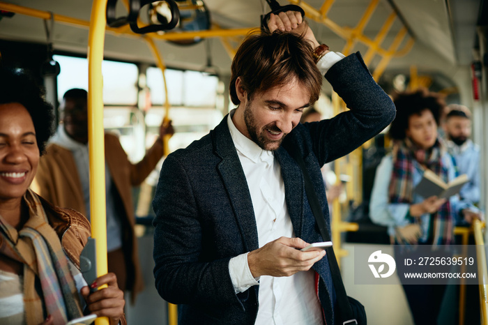 Happy entrepreneur using smart phone while traveling to work by bus.