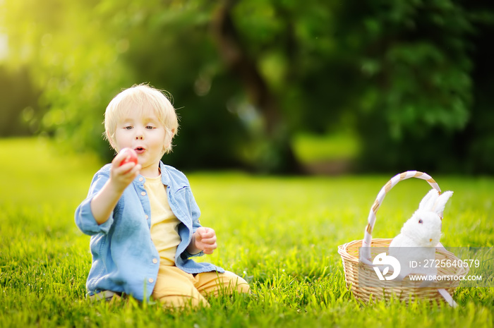 Charming little boy hunting for easter egg in spring park on Easter day