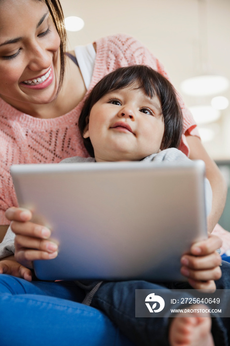 婴儿和母亲坐在家里用数字平板电脑