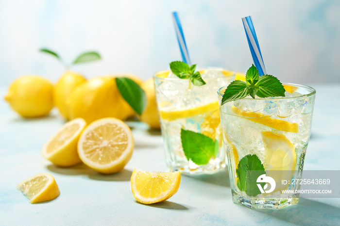 two glasses of lemonade with fresh lemon on turquoise background