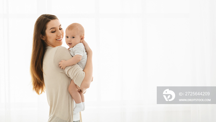 Pretty mom holding cute smiling baby in hands