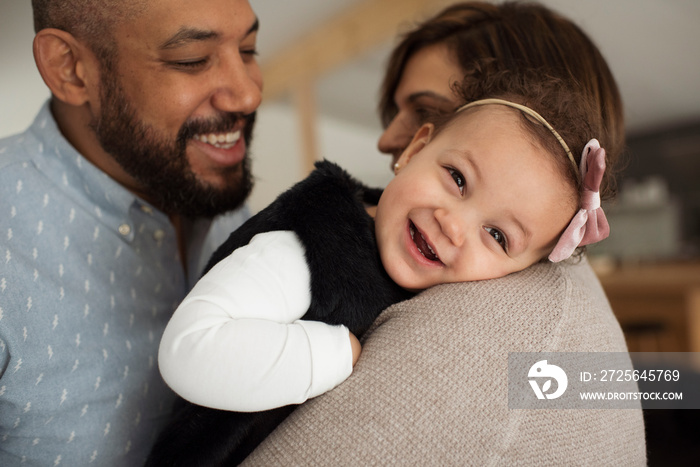 Close-up of happy father looking at cute daughter being carried by mother in room