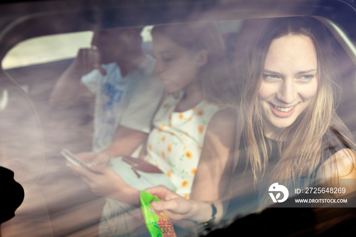 Woman looking out car window while on road trip with friends