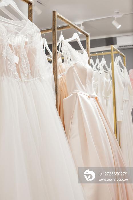Assortment of dresses hanging on a hanger on the background studio. Fashion wedding trends. Interior