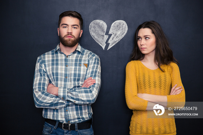 Couple after argument standing separately over blackboard background