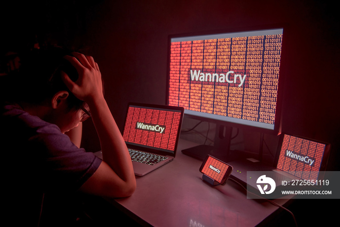 Young Asian male frustrated, confused and headache by WannaCry ransomware attack on desktop screen, 