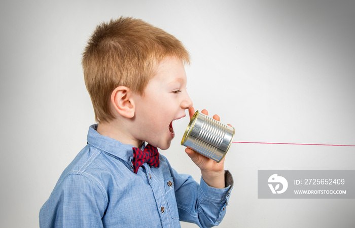 young boy is talking with tin can telephone