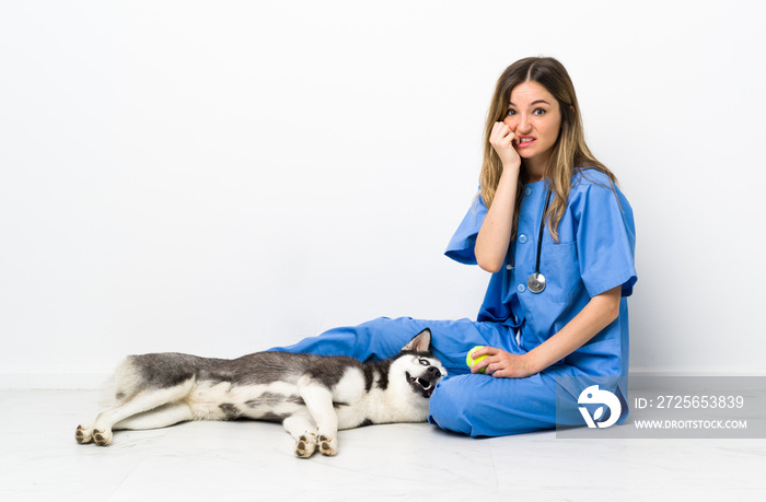 Veterinary doctor with Siberian Husky dog sitting on the floor nervous and scared