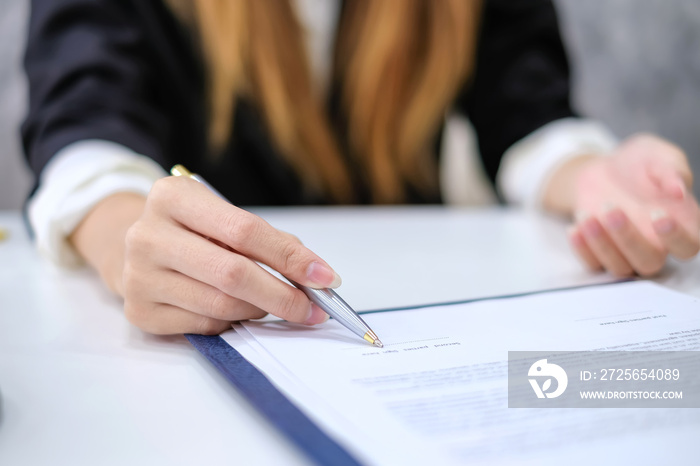 Close-up of a business woman hand pointing signing contract at the office.