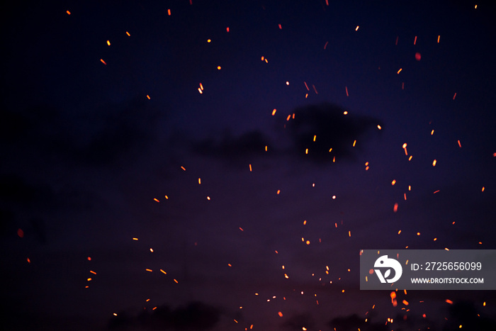 Large burning bonfire with soft glowing flame throws flying sparkles all around. Romantic summer eve