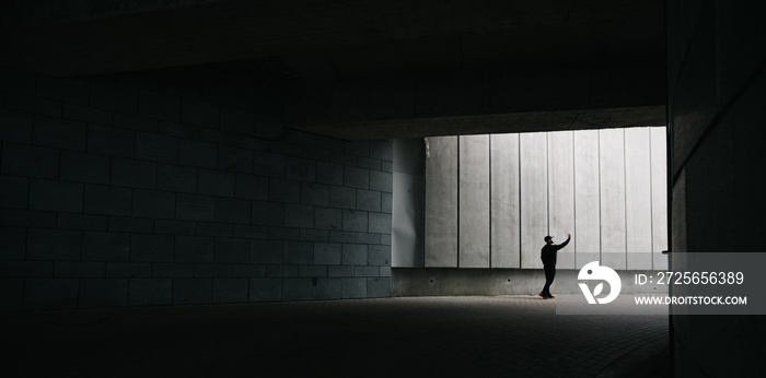 Man in a tunnel exit looking up and raising his hand up