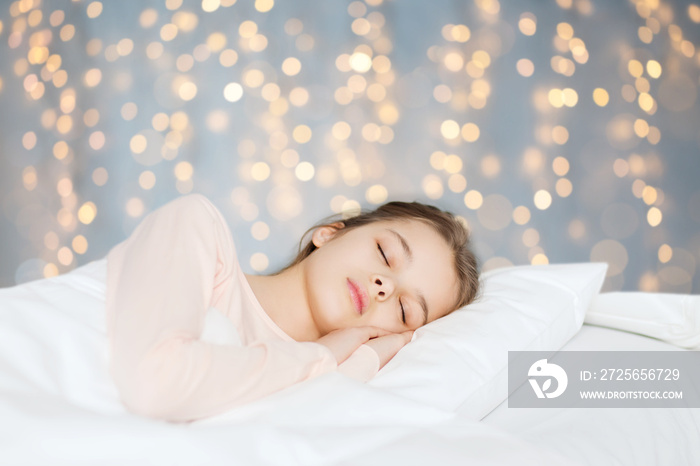 girl sleeping in bed over holidays lights