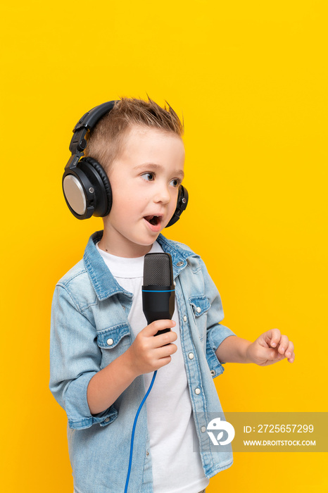 Portrait of singing little kid with headphones and microphone