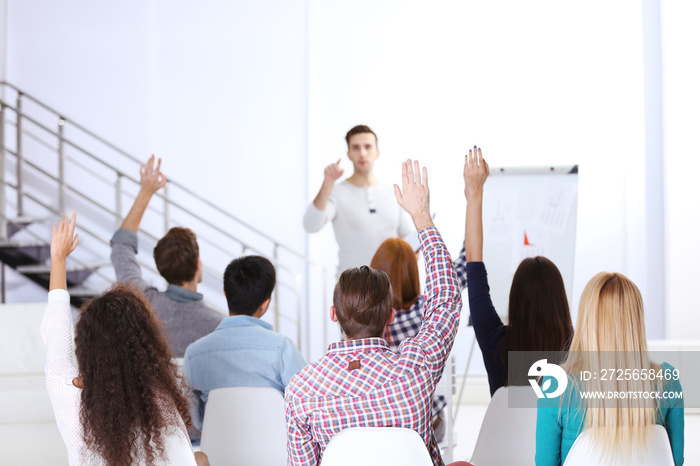 Young colleagues raising hands at the business meeting in office