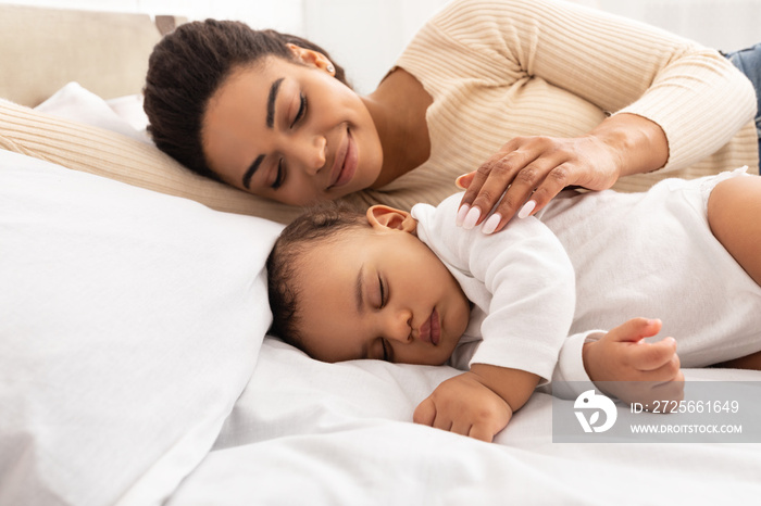 Loving Black Mom Hugging Sleeping Baby Lying In Bed Indoor