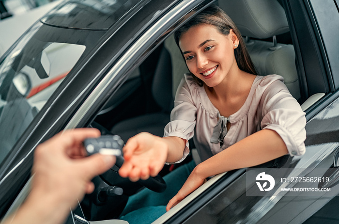 Young woman receiving the keys of her new car. Woman buying the car.