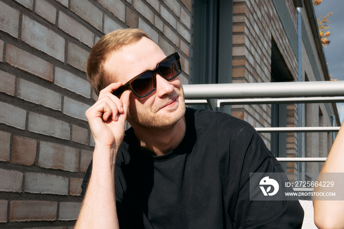 Young man sitting on the balcony with sunglasses on