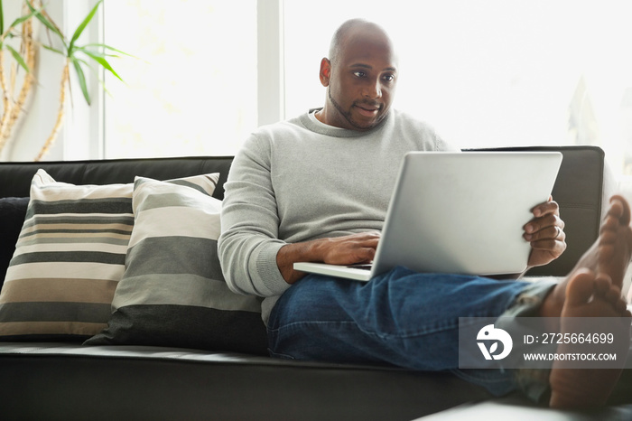 Man using laptop while sitting on sofa in living room