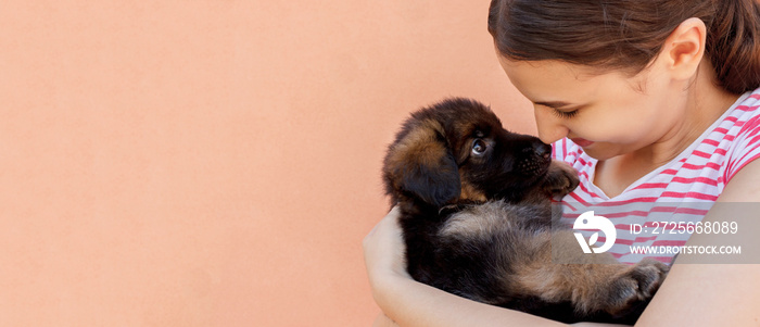 Beautiful woman holding and looking into black puppys eyes