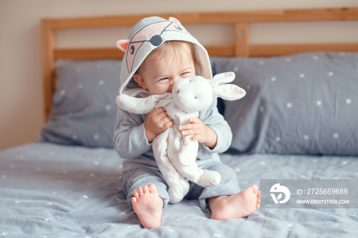 Portrait of cute adorable Caucasian blonde smiling baby girl with blue eyes in grey pajama with fox 