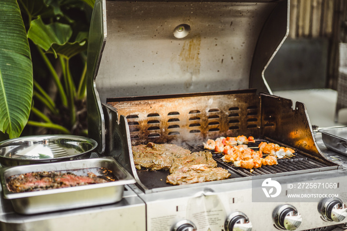 A man in tattoos makes barbecue grill meat outdoors.