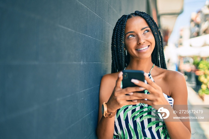 Young african american woman smiling happy using smartphone at the city.