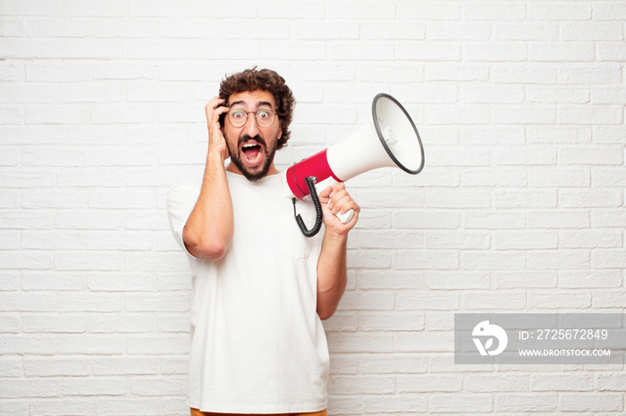 young dumb man with a crazy, amazed look of surprise, holding head with both hands, pulling hair.