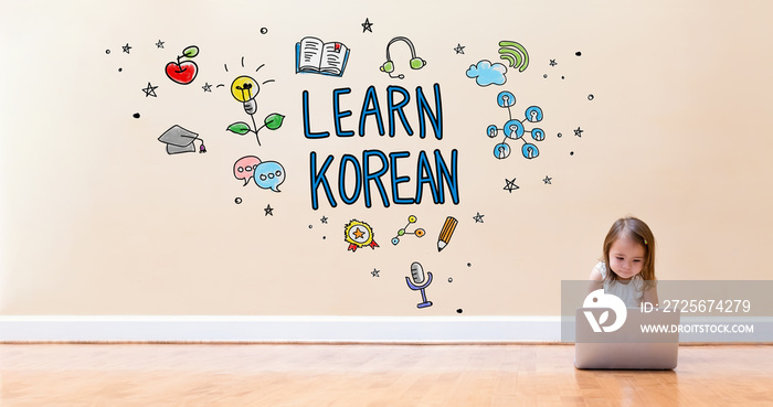 在地板上用笔记本电脑和小女孩一起学习韩语文本