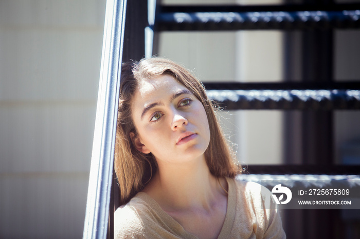 Close-up of thoughtful sad woman sitting on steps during sunny day