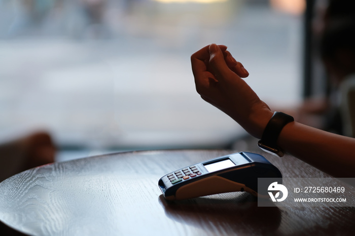 close up hand using smart watch pay over POS terminal in bar counter