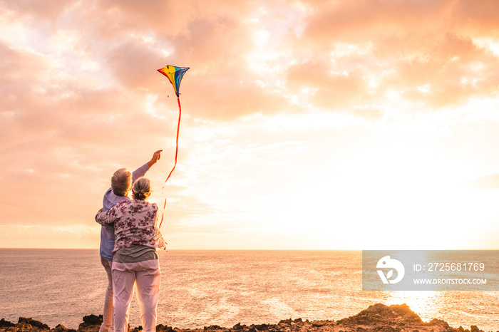 close up and portrait of two old and mature people playing and enjoying with a flaying kite at the b