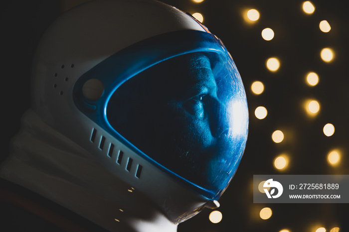 Spaceman wearing astronaut helmet with twinkle lights in the background