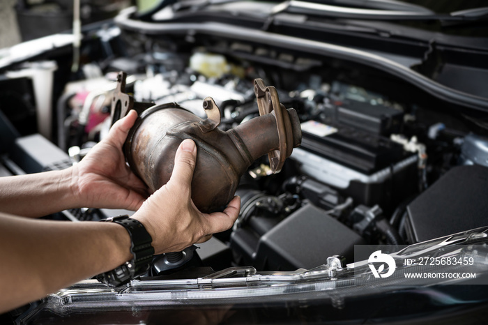 Close up old catalytic converter in hand Technician remove from engine gasoline car dust clogged con