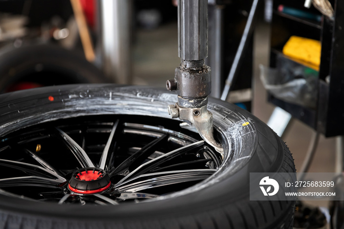 Wheel with tire on tire changing machine in auto repair service.