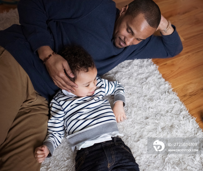 High angle view of loving father with cute son relaxing on rug at home