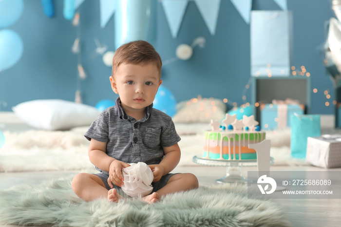 Cute little boy sitting on fluffy rug in room decorated for birthday party