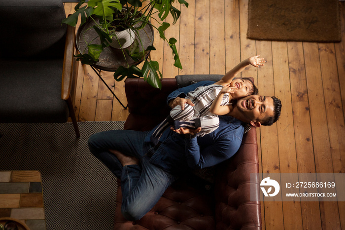 High angle view of happy father playing with daughter on sofa at home