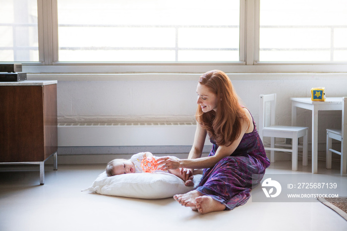 Mother playing with baby girl (6-11 months) in living room