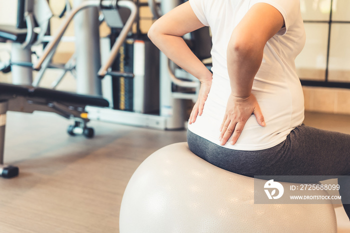 Active pregnant woman exercise in fitness center at yoga room. The young expecting mother holding ba