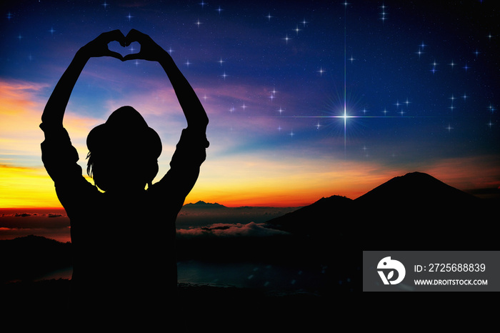 Silhouette of a girl holding heart-shape symbol for love on a starry night sky. My astronomy work.