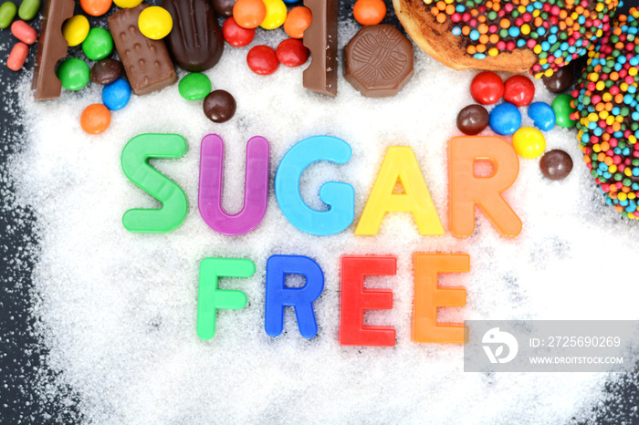 Health concept with multicolored letter blocks on granulated white sugar spelling “sugar free”