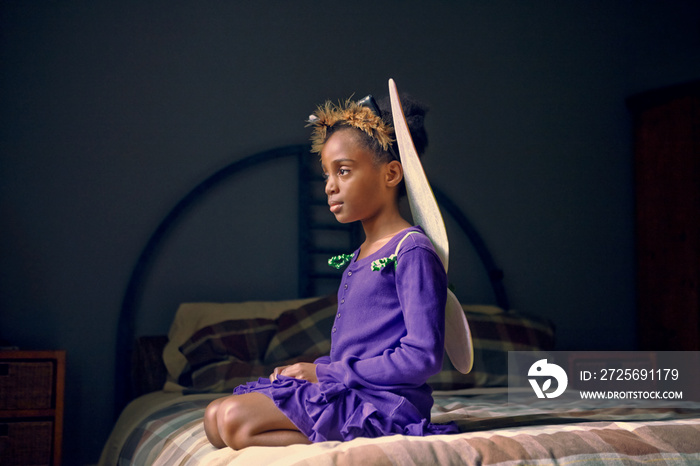 Girl in Halloween costume sitting on bed