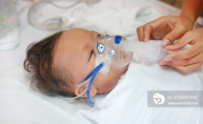 Toddler boy using nebulizer to cure asthma or pneumonia disease . Sick baby boy rest on patients bed