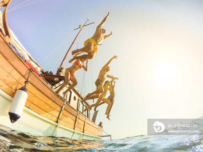 Happy friends diving from sailing boat into the sea