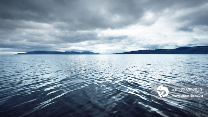 Panoramic view of the rocky river shores from the water. Trees, hills and mountains in the backgroun