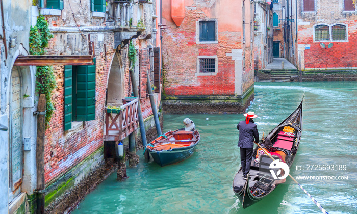 Venetian gondolier punting gondola through green canal waters of Venice Italy