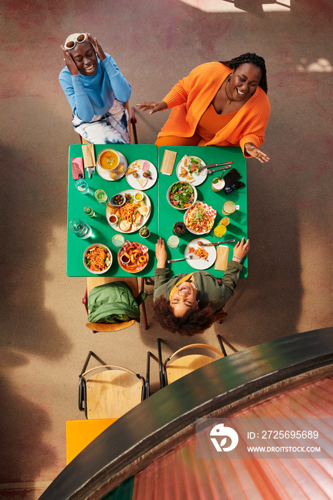 High angle view of female friends laughing while having meal in restaurant