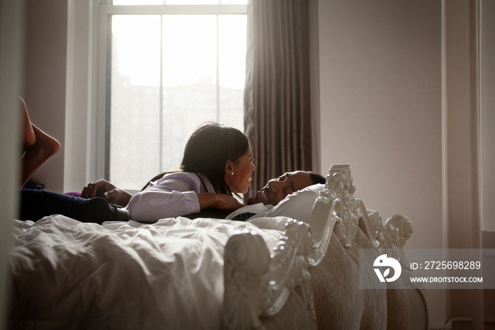 Well-dressed couple laughing on bed