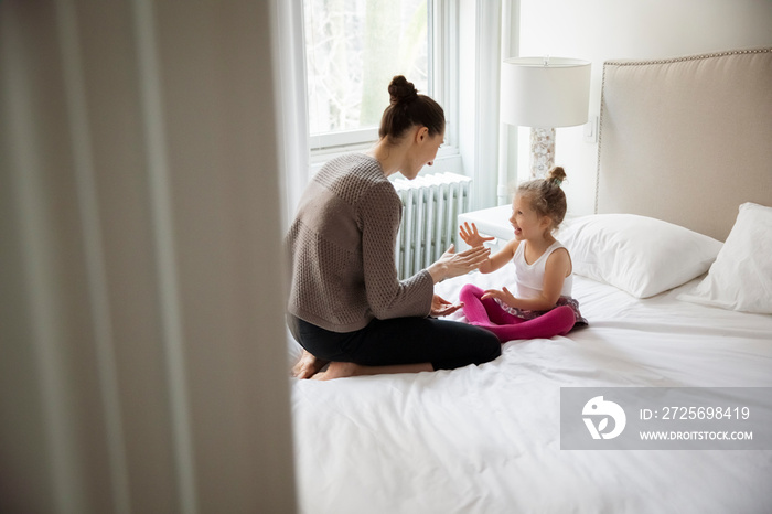 High angle view of happy mother playing with cute daughter on bed at home seen through doorway